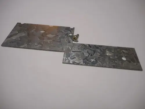 Zwei verzinkte Metallplatten mit einer Befestigungsschraube. Die Platten sind teilweise überlappt. Produkt von Remeha.